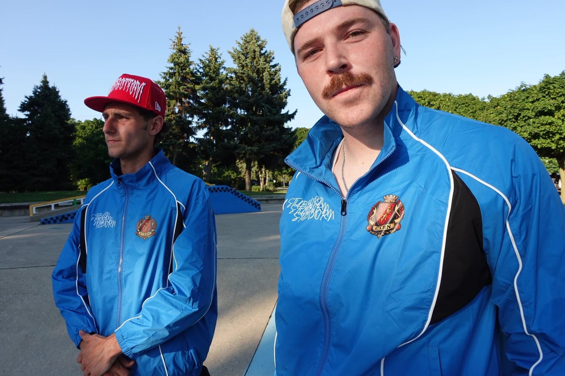 Two people at a skate park in the blue Stubborn Tracksuit